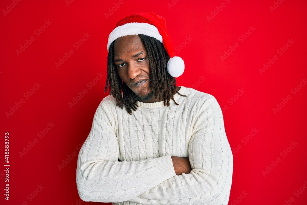 African american man with braids wearing christmas hat skeptic and nervous, disapproving expression on face with crossed arms. negative person.