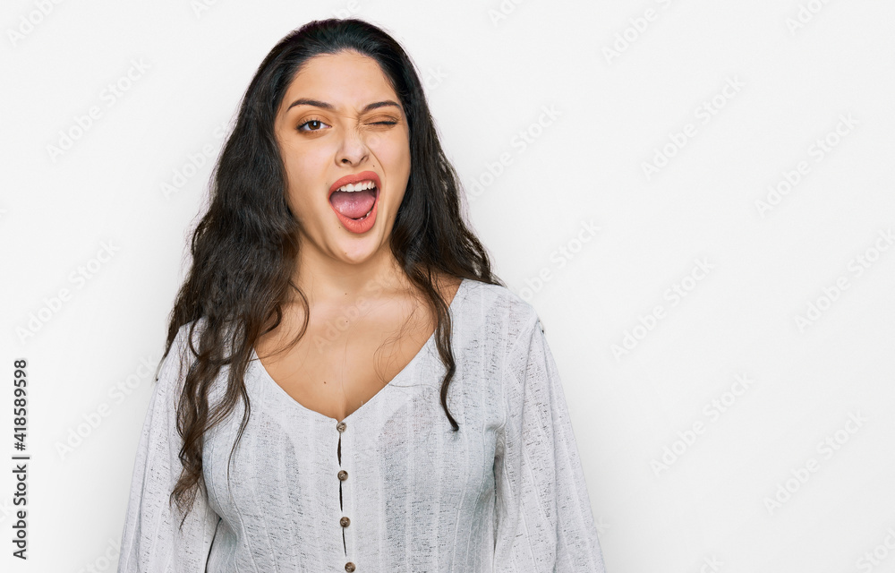 Brunette young woman wearing casual clothes winking looking at the camera with sexy expression, cheerful and happy face. Brunette young woman wearing casual clothes winking looking at the camera with sexy expression, cheerful and happy face.