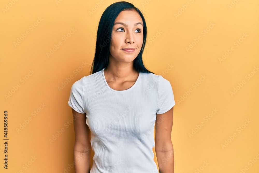 Beautiful hispanic woman wearing casual white tshirt smiling looking to the side and staring away thinking. Beautiful hispanic woman wearing casual white tshirt smiling looking to the side and staring away thinking.