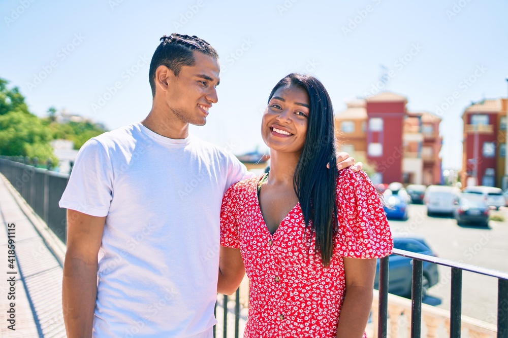 Naklejka premium Young latin couple smiling happy hugging at street of city.