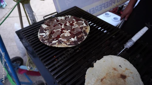 Man cooking traditional Mexican tlayuda on a griddle in the street. photo