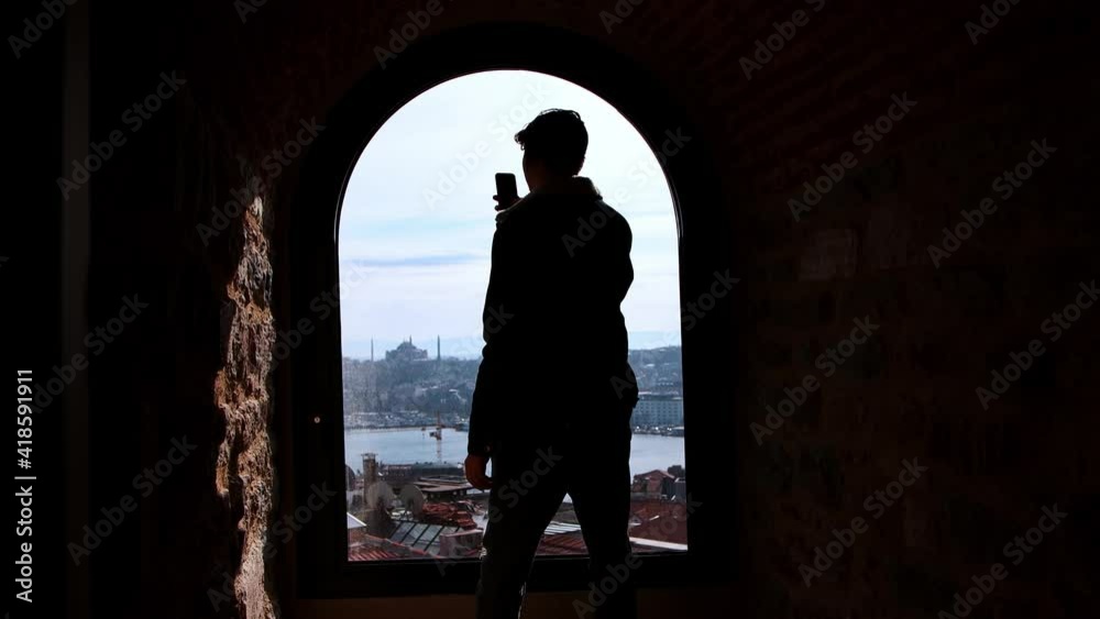 A man traveler walking on the observation tower and shooting the view of Istanbul on his phone A man traveler walking on the observation tower and shooting the view of Istanbul on his phone