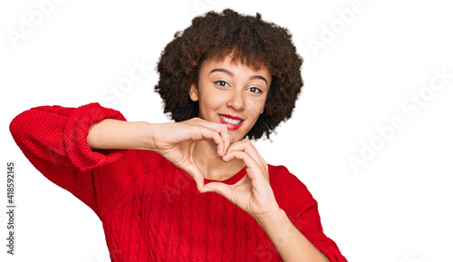 Young hispanic girl wearing casual clothes smiling in love doing heart symbol shape with hands. romantic concept.