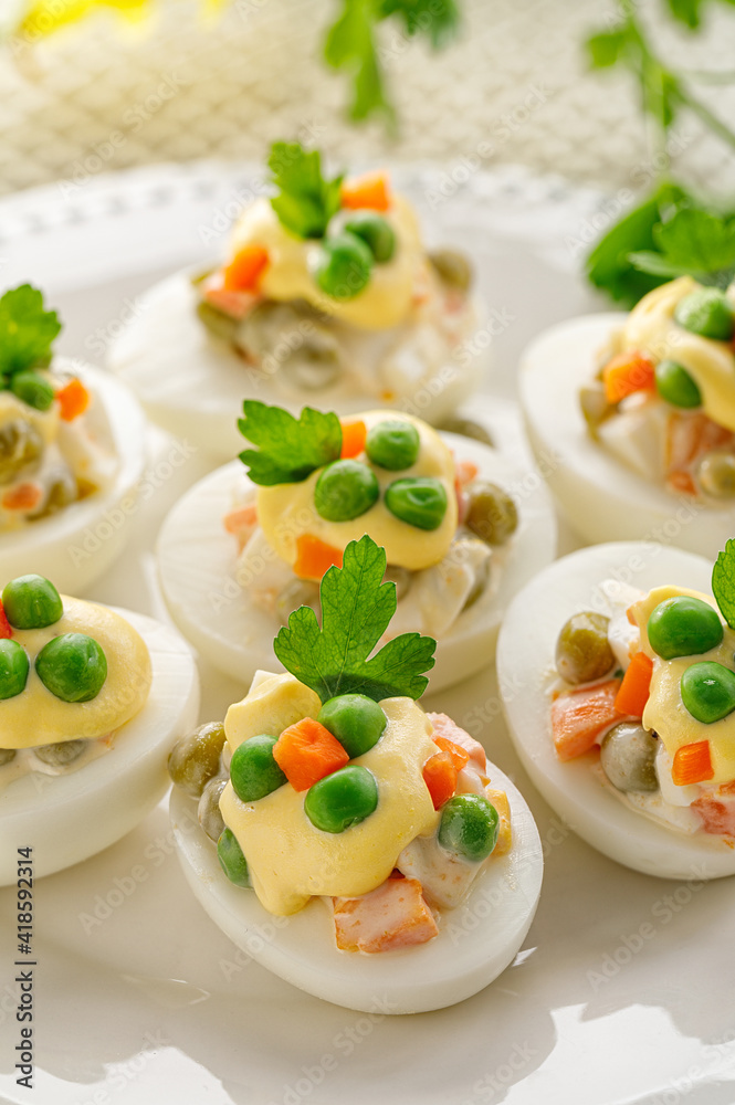 Easter boiled eggs stuffed with vegetable salad with mayonnaise served on a white plate close up view Easter boiled eggs stuffed with vegetable salad with mayonnaise served on a white plate close up view