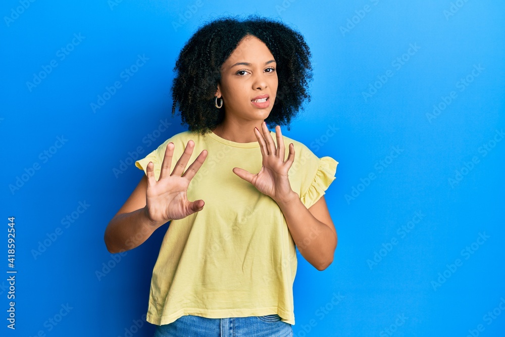 Young african american girl wearing casual clothes disgusted expression, displeased and fearful doing disgust face because aversion reaction. with hands raised Young african american girl wearing casual clothes disgusted expression, displeased and fearful doing disgust face because aversion reaction. with hands raised