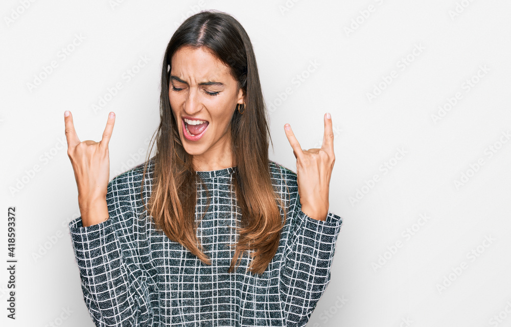 Young beautiful woman wearing casual clothes shouting with crazy expression doing rock symbol with hands up. music star. heavy concept. Young beautiful woman wearing casual clothes shouting with crazy expression doing rock symbol with hands up. music star. heavy concept.