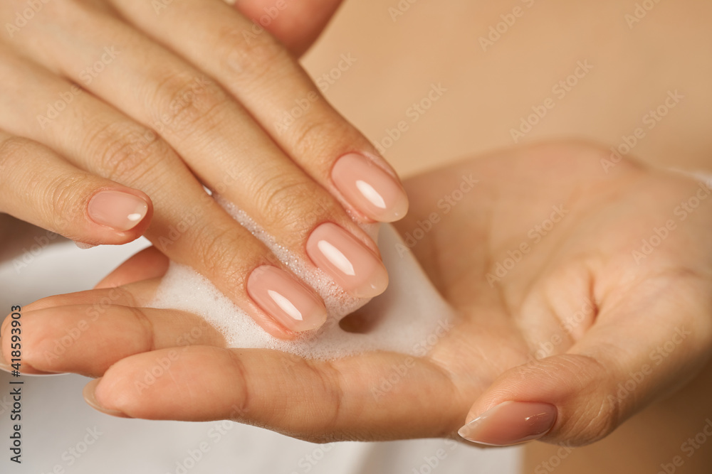 Close up of female hands holding, applying gentle foam facial cleanser Close up of female hands holding, applying gentle foam facial cleanser