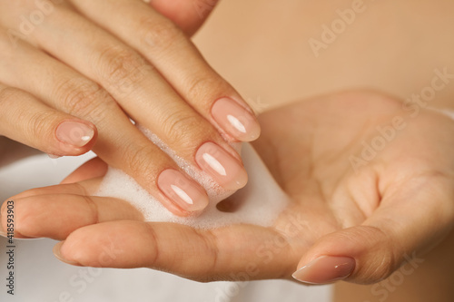 Close up of female hands holding  applying gentle foam facial cleanser