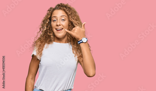 Beautiful caucasian teenager girl wearing casual white tshirt smiling doing phone gesture with hand and fingers like talking on the telephone. communicating concepts.