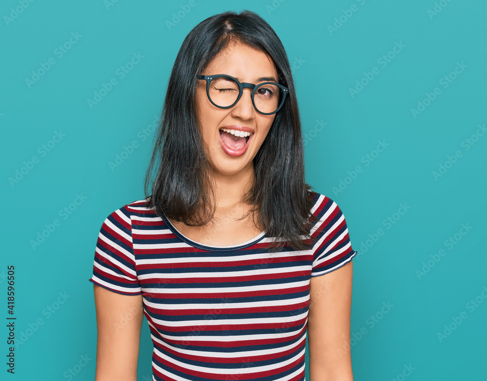 Beautiful asian young woman wearing casual clothes and glasses winking looking at the camera with sexy expression, cheerful and happy face. Beautiful asian young woman wearing casual clothes and glasses winking looking at the camera with sexy expression, cheerful and happy face.