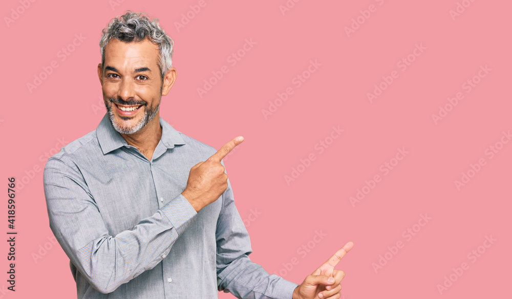 Middle age grey-haired man wearing casual clothes smiling and looking at the camera pointing with two hands and fingers to the side. Middle age grey-haired man wearing casual clothes smiling and looking at the camera pointing with two hands and fingers to the side.