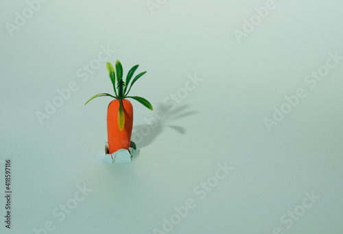 A carrot grows out of torn paper and casts a shadow on the background.