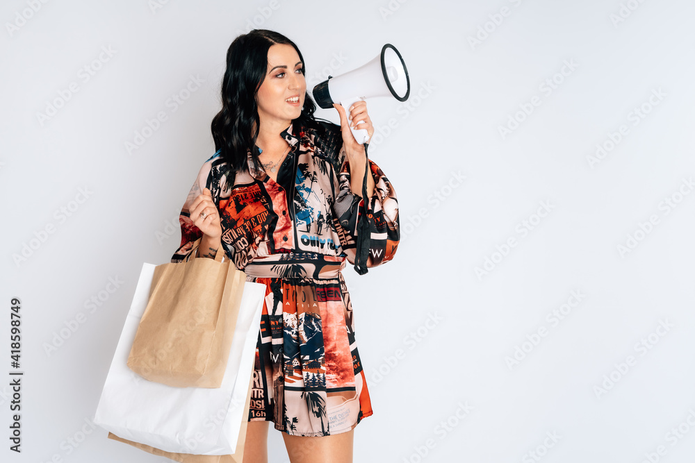 Happy smiling beautiful girl with shopping bags shout into megaphone white background short dress mock up copy space hold package bag black overknees Happy smiling beautiful girl with shopping bags shout into megaphone white background short dress mock up copy space hold package bag black overknees