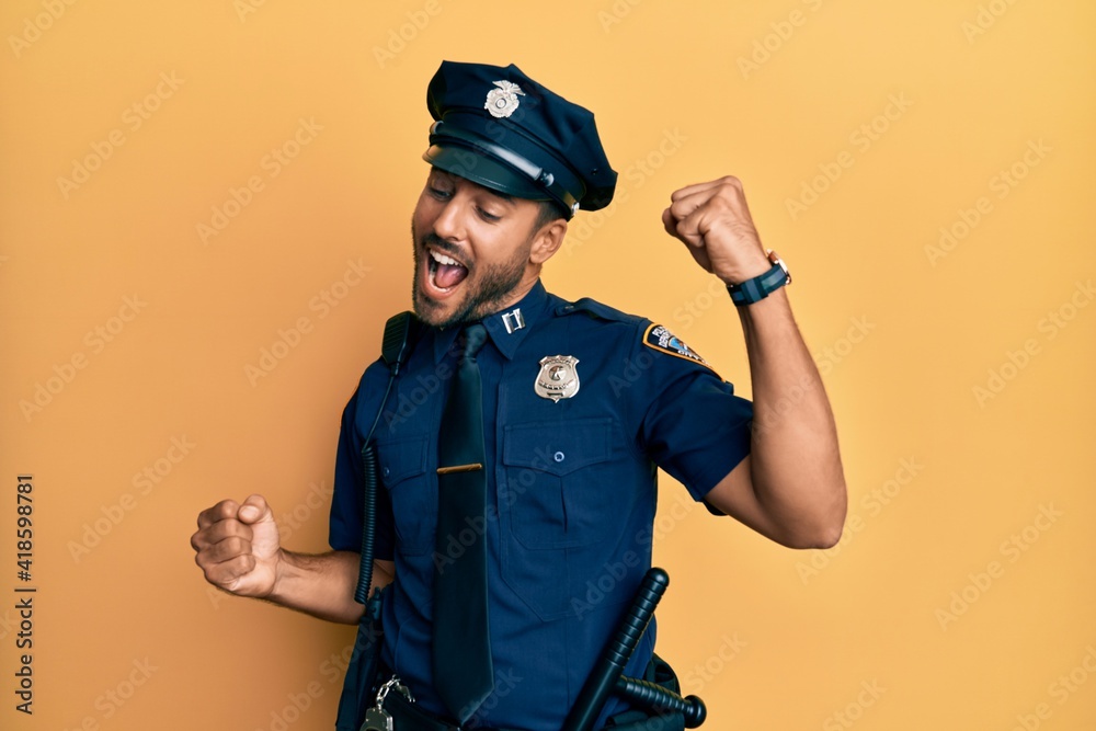 Handsome hispanic man wearing police uniform dancing happy and cheerful, smiling moving casual and confident listening to music Handsome hispanic man wearing police uniform dancing happy and cheerful, smiling moving casual and confident listening to music