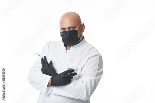 Mature doctor in a medical mask and protective gloves holds syringes with a medicine or vaccine in crossed hands. Portrait isolated on white with copy space. photo