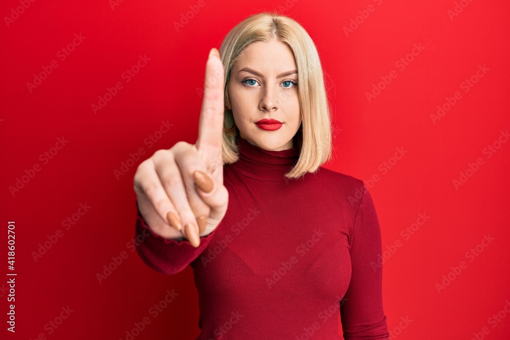 Young blonde woman wearing casual clothes pointing with finger up and angry expression, showing no gesture Young blonde woman wearing casual clothes pointing with finger up and angry expression, showing no gesture