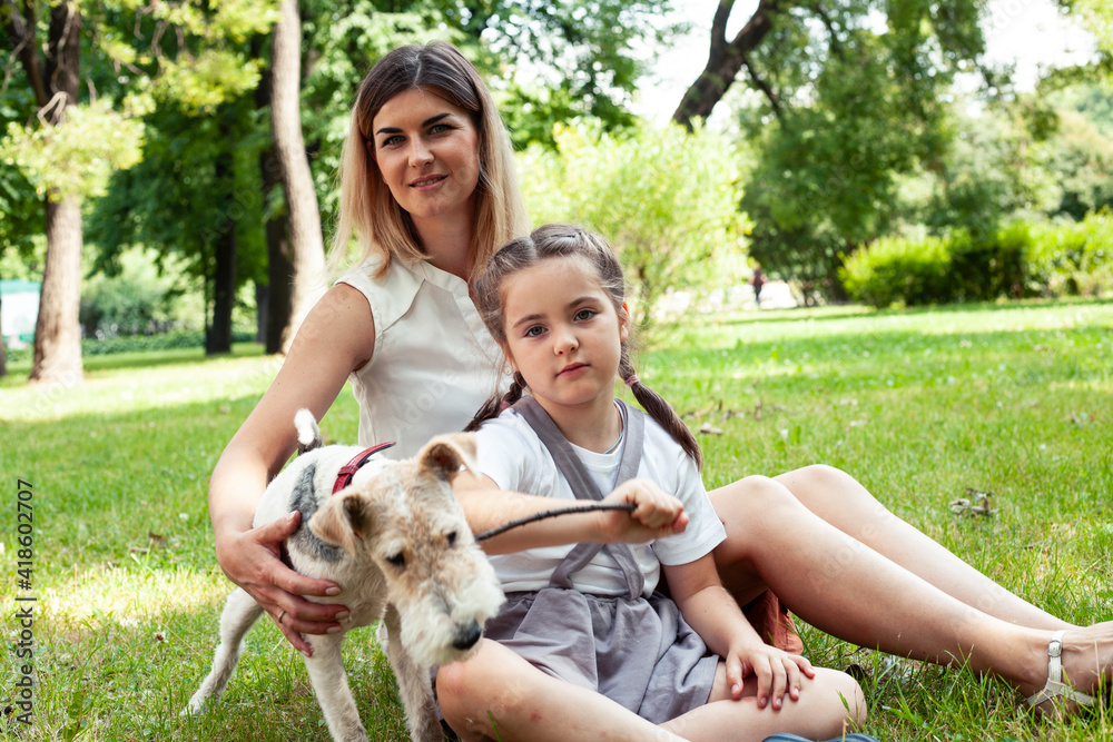 young pretty caucasian mother walking with little cute daughter and dog fox terrier, lifestyle people concept young pretty caucasian mother walking with little cute daughter and dog fox terrier, lifestyle people concept