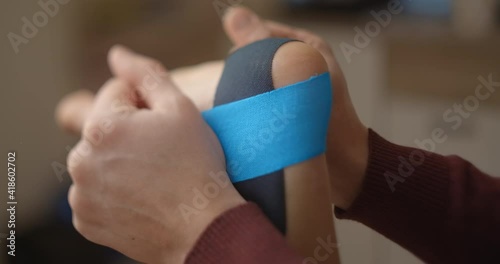 Physiotherapist sticks kinesio tapes to the heel of female patient, kinesiology taping, kinesiological therapy, athlete are recovering after injury, 4k 60p Prores HQ 10 bit photo