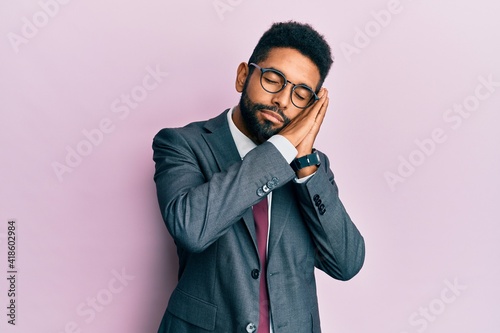 Handsome hispanic business man with beard wearing business suit and tie sleeping tired dreaming and posing with hands together while smiling with closed eyes. © Krakenimages.com