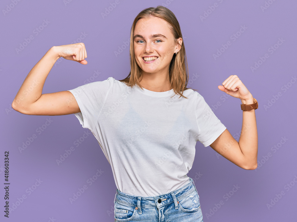 Obraz premium Beautiful young blonde woman wearing casual white t shirt showing arms muscles smiling proud. fitness concept.