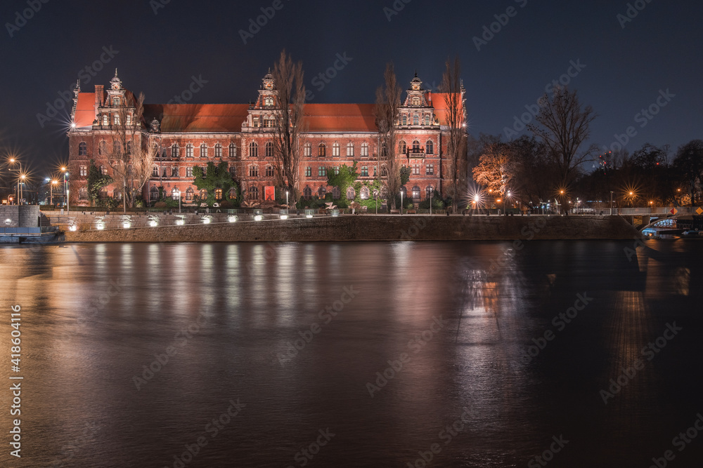 Wroclaw National Museum on the Odra River, night view from the shore.