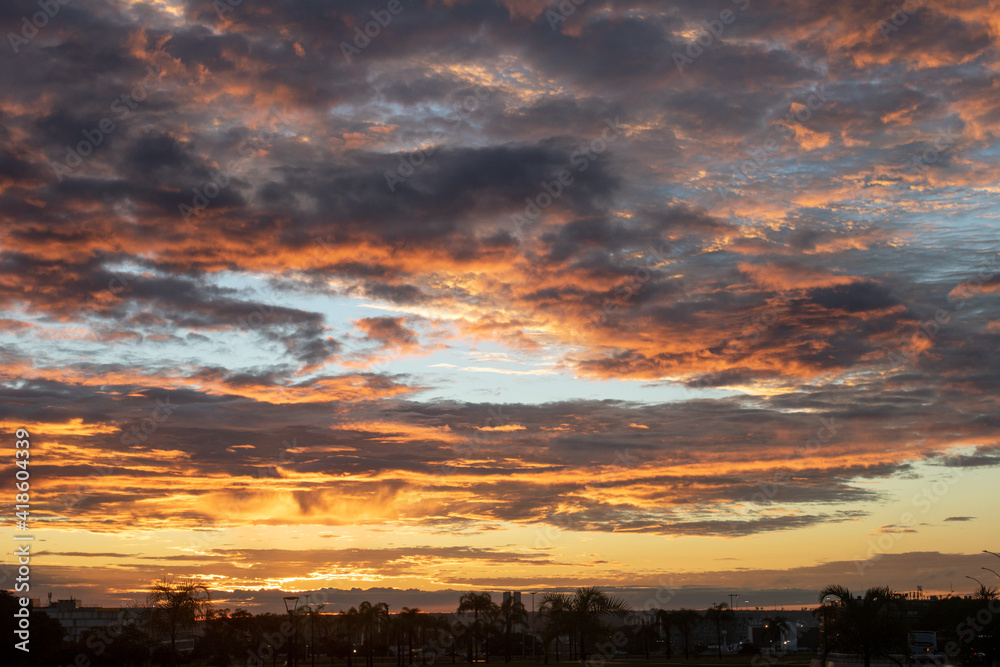 Fototapeta premium Black and orange cotton-textured clouds spread across a blue sky to the horizon