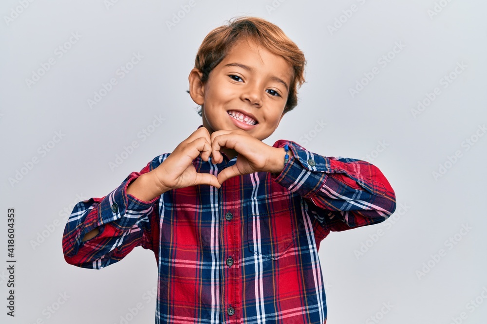 Adorable latin kid wearing casual clothes smiling in love doing heart symbol shape with hands. romantic concept. Adorable latin kid wearing casual clothes smiling in love doing heart symbol shape with hands. romantic concept.