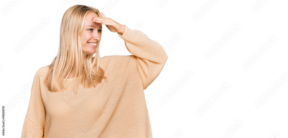 Fototapeta premium Young blonde girl wearing casual clothes very happy and smiling looking far away with hand over head. searching concept.