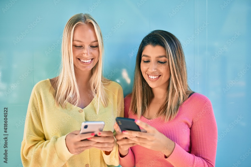 Two beautiful and young girl friends together having fun at the city using smartphone Two beautiful and young girl friends together having fun at the city using smartphone