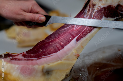 Iberian ham cut into small slices with a knife.