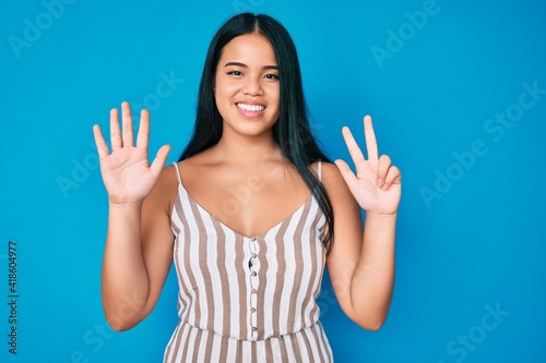 Young beautiful asian girl wearing casual clothes showing and pointing up with fingers number eight while smiling confident and happy.