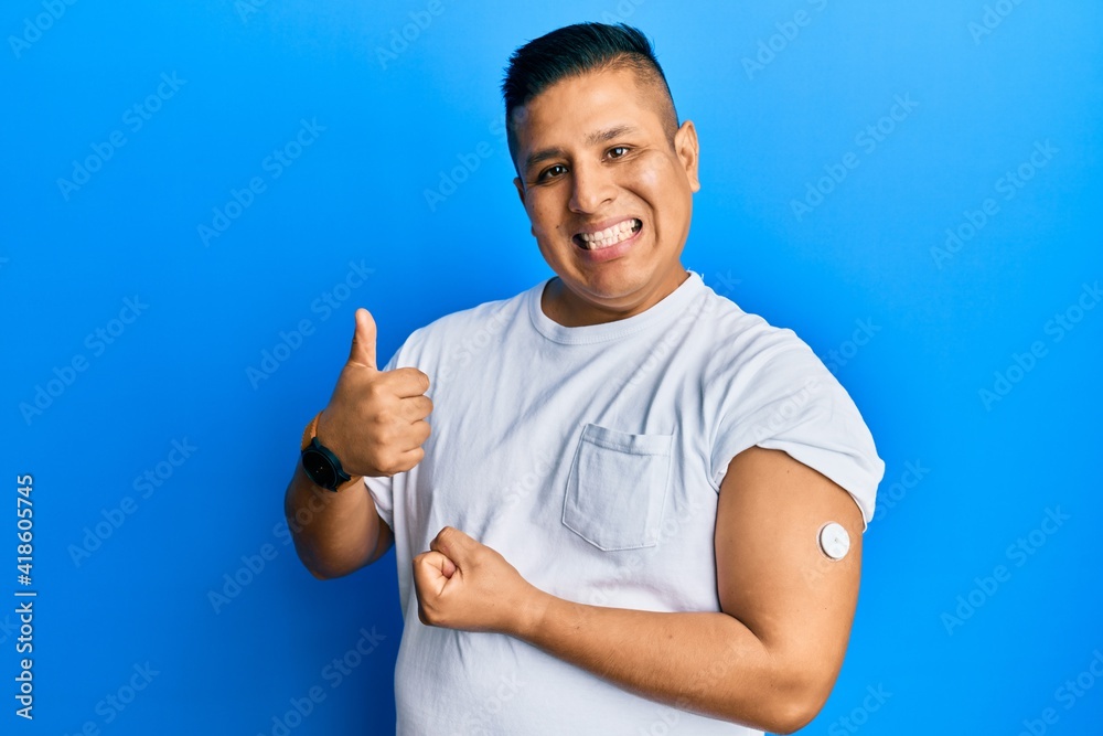 Young latin man using glucose meter button smiling happy and positive, thumb up doing excellent and approval sign Young latin man using glucose meter button smiling happy and positive, thumb up doing excellent and approval sign