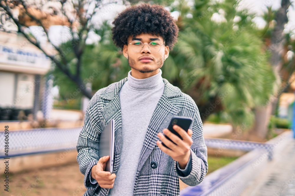 Fototapeta premium Young african american businessman with serious expression using smartphone at the city.