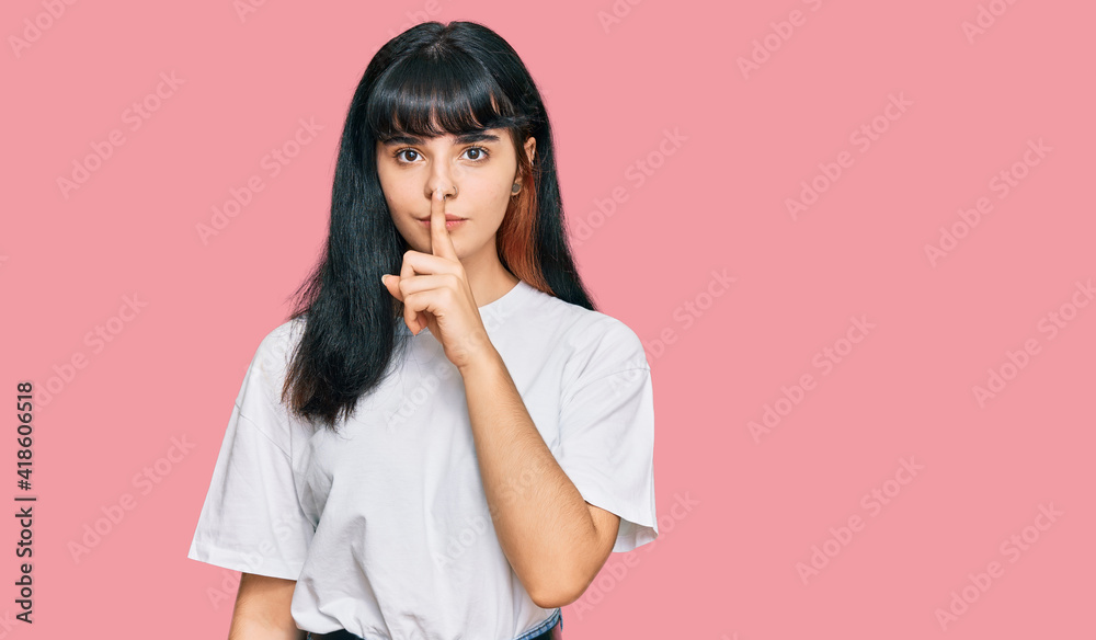 Young hispanic girl wearing casual clothes asking to be quiet with finger on lips. silence and secret concept.