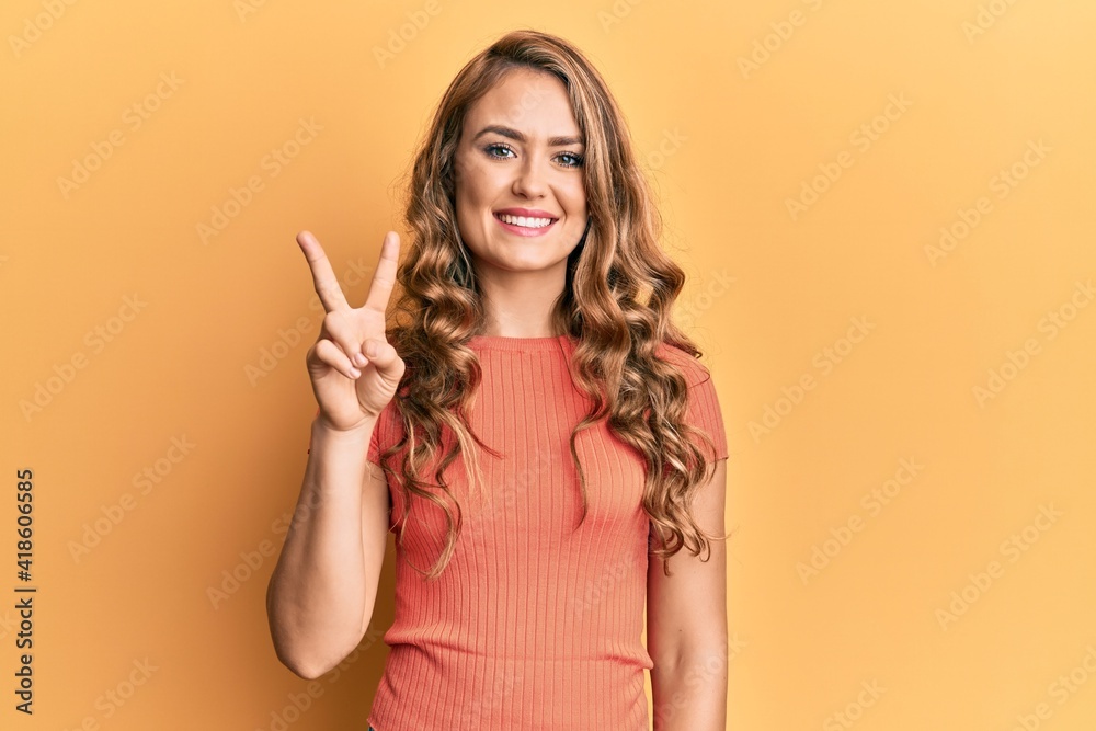 Young blonde girl wearing casual clothes showing and pointing up with fingers number two while smiling confident and happy. Young blonde girl wearing casual clothes showing and pointing up with fingers number two while smiling confident and happy.