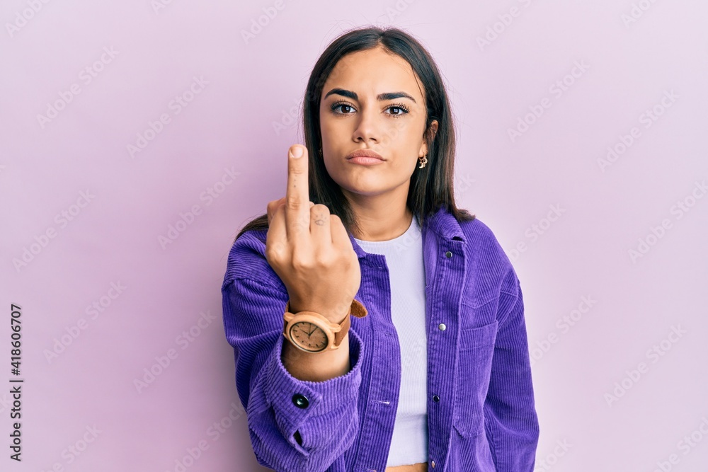 Young brunette woman wearing casual clothes showing middle finger, impolite and rude fuck off expression Young brunette woman wearing casual clothes showing middle finger, impolite and rude fuck off expression
