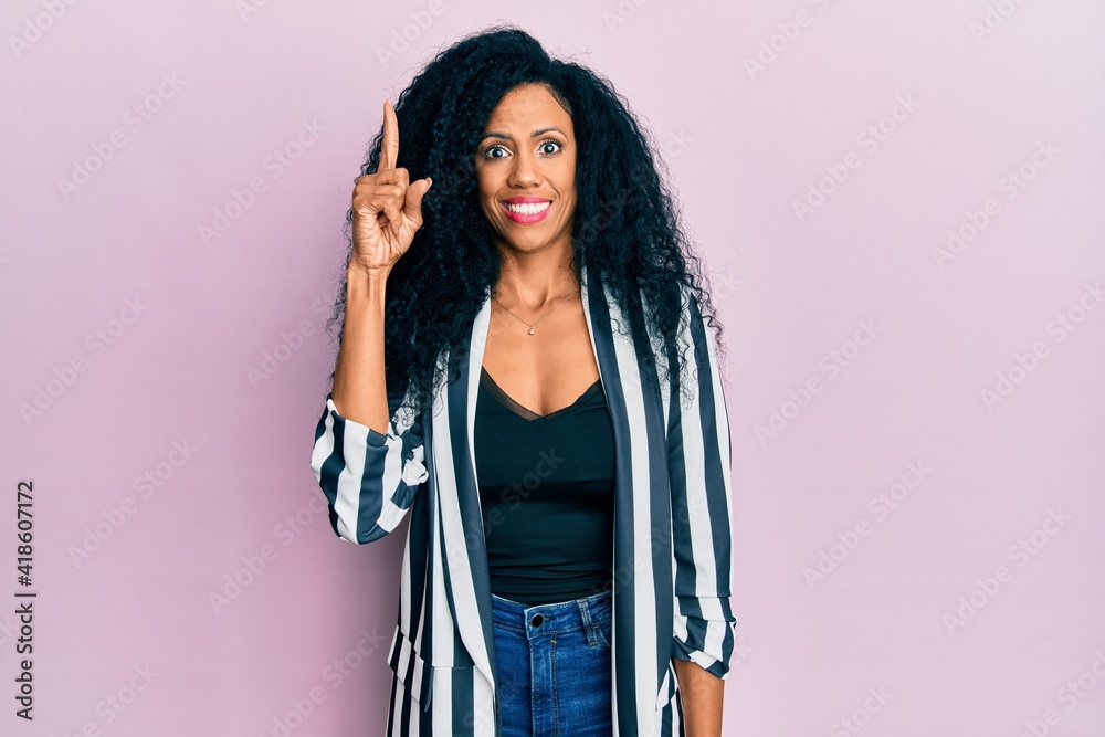 Middle age african american woman wearing casual clothes pointing finger up with successful idea. exited and happy. number one.