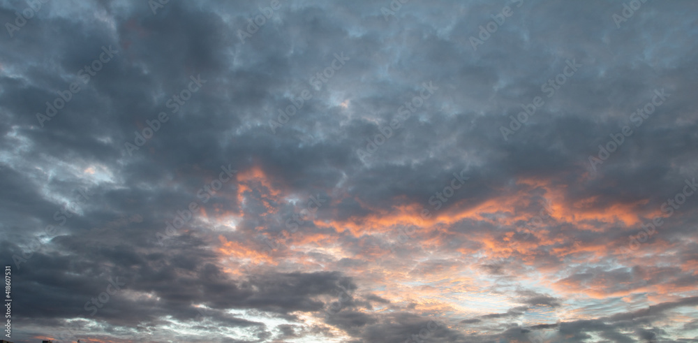 White and orange cotton-textured clouds spread across a blue sky to the horizon