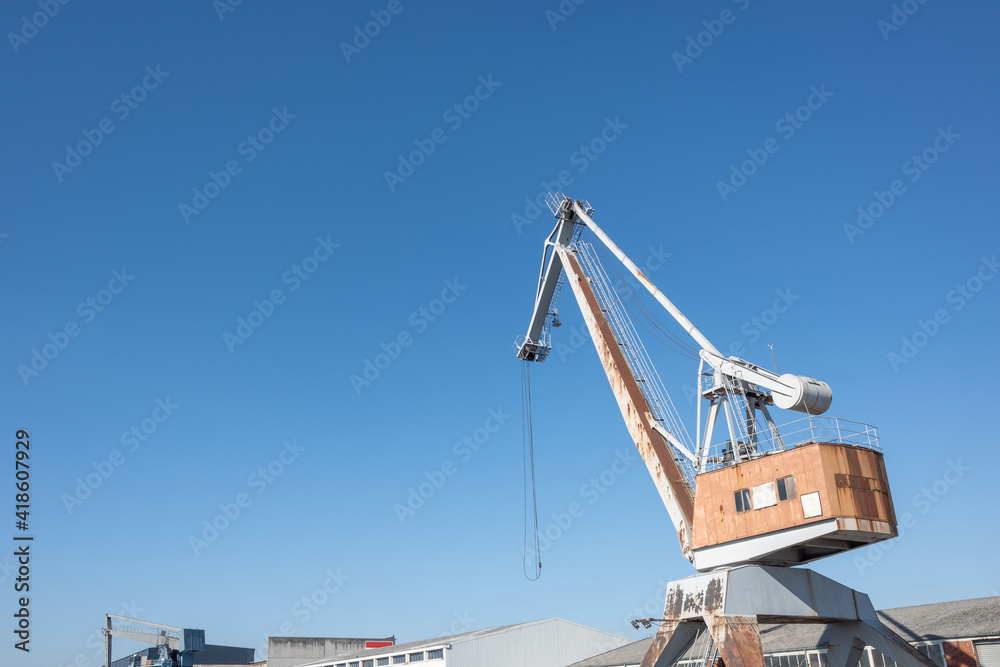 Shipyard cranes or portal cranes at logistic river harbour port against blue sky. Shipyard cranes or portal cranes at logistic river harbour port against blue sky.