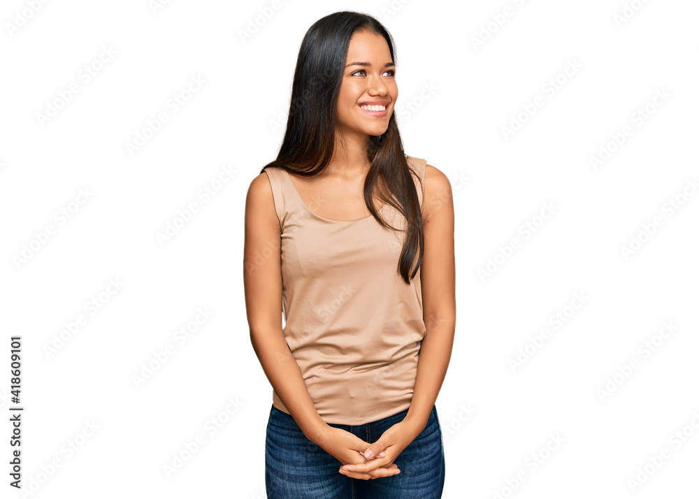 Fototapeta premium Beautiful hispanic woman wearing casual clothes looking away to side with smile on face, natural expression. laughing confident.