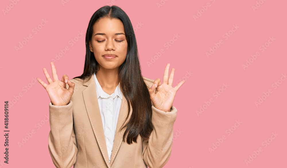 Beautiful hispanic woman wearing business jacket relax and smiling with eyes closed doing meditation gesture with fingers. yoga concept. Beautiful hispanic woman wearing business jacket relax and smiling with eyes closed doing meditation gesture with fingers. yoga concept.