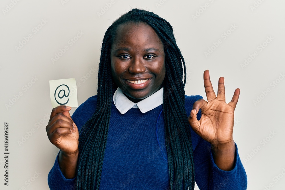 Young black woman with braids holding email symbol on paper doing ok sign with fingers, smiling friendly gesturing excellent symbol Young black woman with braids holding email symbol on paper doing ok sign with fingers, smiling friendly gesturing excellent symbol