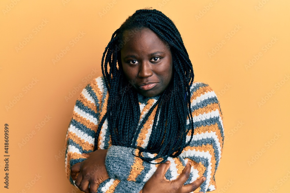 Young black woman with braids wearing casual winter sweater shaking and freezing for winter cold with sad and shock expression on face