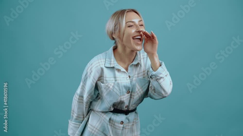 Cheerful and hairy young woman, girl putting her hand to her mouth Beautiful young blonde, blonde, in her house shirt, blue. Isolated on blue background, Concept of life. People's emotions. 4k