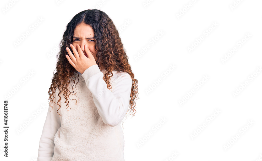Beautiful kid girl with curly hair wearing casual clothes smelling something stinky and disgusting, intolerable smell, holding breath with fingers on nose. bad smell Beautiful kid girl with curly hair wearing casual clothes smelling something stinky and disgusting, intolerable smell, holding breath with fingers on nose. bad smell