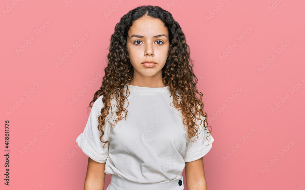 Teenager hispanic girl wearing casual white t shirt with serious expression on face. simple and natural looking at the camera. Teenager hispanic girl wearing casual white t shirt with serious expression on face. simple and natural looking at the camera.