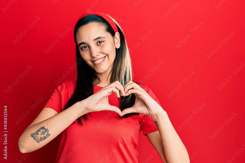 Young hispanic woman wearing casual red t shirt smiling in love doing heart symbol shape with hands. romantic concept. Young hispanic woman wearing casual red t shirt smiling in love doing heart symbol shape with hands. romantic concept.