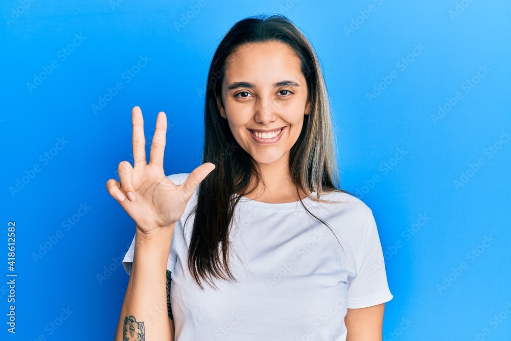 Young hispanic woman wearing casual white t shirt showing and pointing up with fingers number three while smiling confident and happy. Young hispanic woman wearing casual white t shirt showing and pointing up with fingers number three while smiling confident and happy.