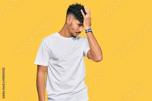 Young arab man wearing casual white t shirt surprised with hand on head for mistake  remember error. forgot  bad memory concept.
