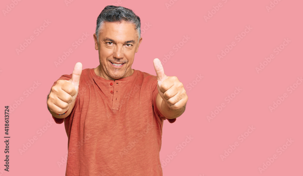 Handsome middle age man wearing casual clothes approving doing positive gesture with hand, thumbs up smiling and happy for success. winner gesture.